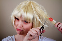 A girl cutting gum that is stuck in their hair with a sad face