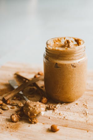 Jar of Opened Peanut Butter with a spoonful on a cutting board 