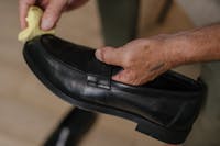 Man cleaning his leather shoe with a cloth to make it shine as brand new